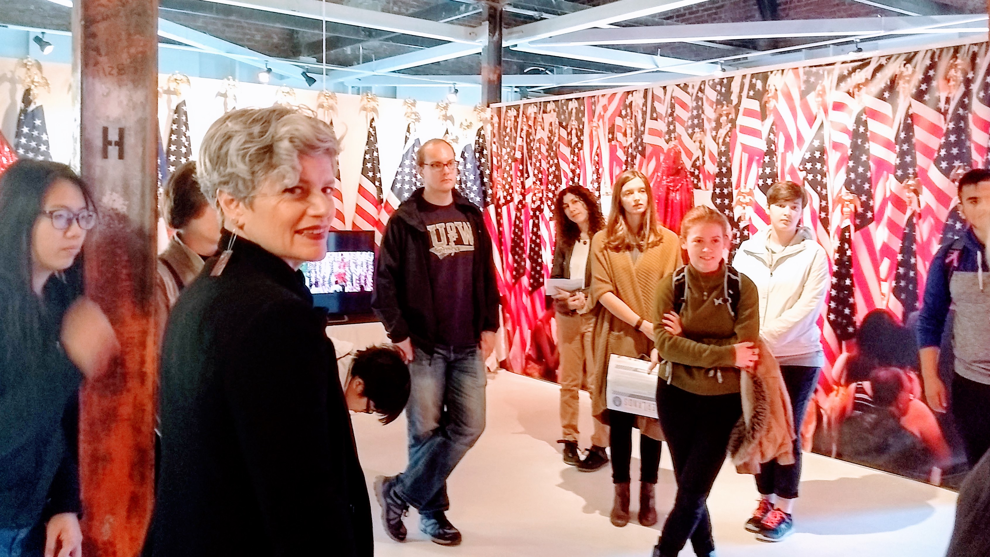 Students in front of art installation using American flags, video, and red sequin burka